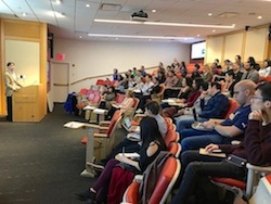 Students watching lecture in auditorium.