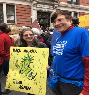 Woman and man holding up protest sign on the street.