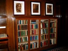 Portraits hang above bookcase.