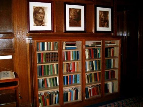 Portraits hang above bookcase. Portraits hang above bookcase.