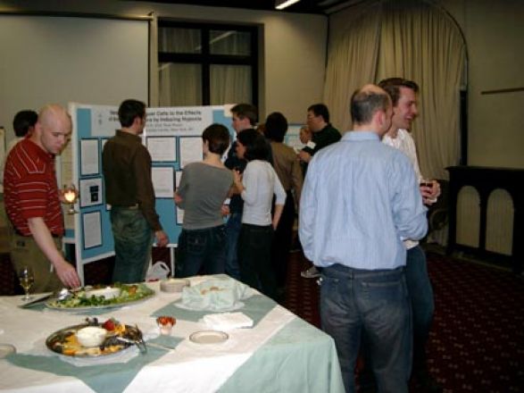 Students socializing and snacking amid poster boards. Students socializing and snacking amid poster boards.