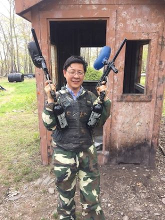 Man standing near house with painball gun.