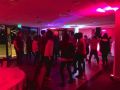 Pink lit party of students dancing.